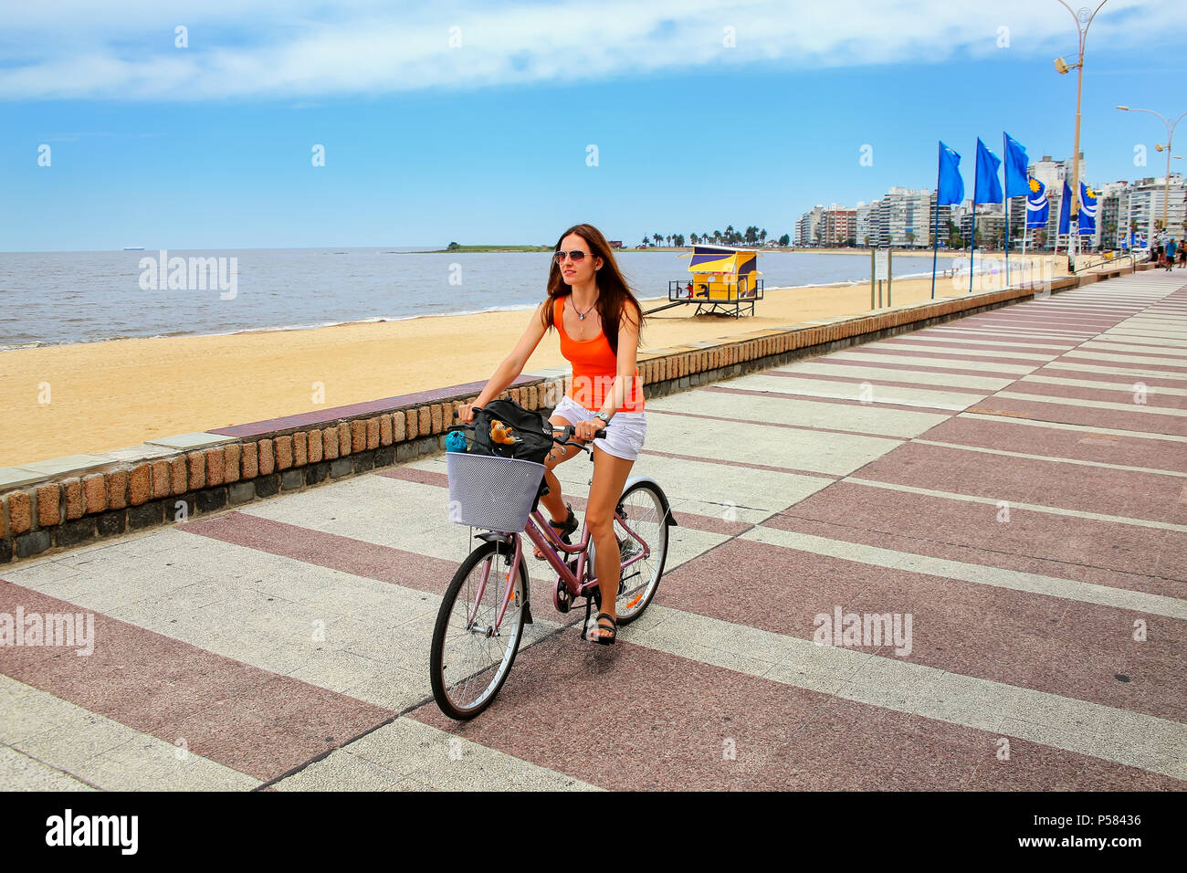 Femme cycliste sur le boulevard le long de la plage de Pocitos à Montevideo, Uruguay. Montevideo est la capitale et la plus grande ville de l'Uruguay Banque D'Images