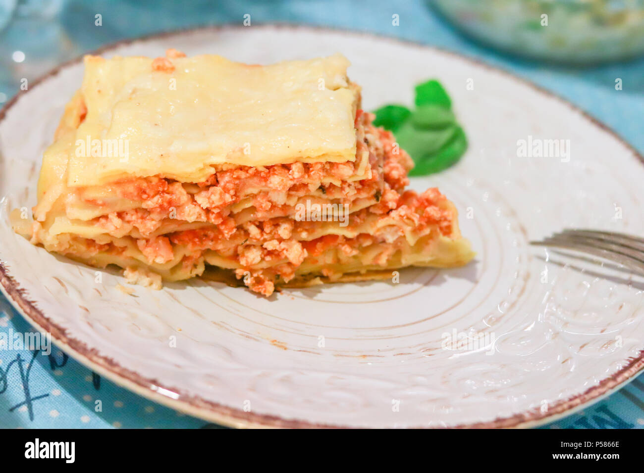 Lasagne Bolognese tranche sur une plaque à motifs blanc au basilic et la  fourchette sur la table Photo Stock - Alamy
