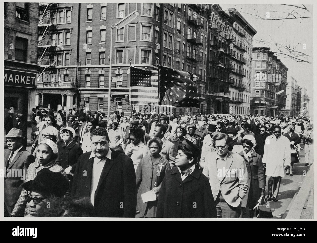 Foule de personnes en deuil, certaines portant des drapeaux, marchant vers le bas 7e Avenue, près de 112e Rue sur chemin de service commémoratif pour le Dr. Martin Luther King Jr. dans Central Park, New York City, New York, USA, le 7 avril 1968 Banque D'Images