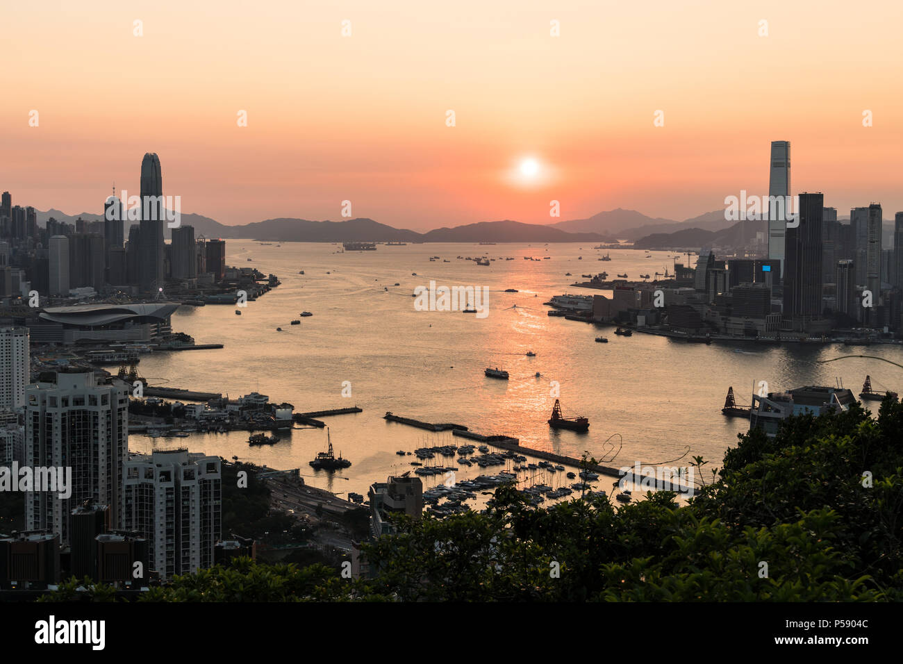 Vue imprenable sur le coucher du soleil au-dessus du port Victoria à Hong Kong avec le gratte-ciel de l'île de Hong Kong Kowloon dans la gauche et sur la droite Banque D'Images