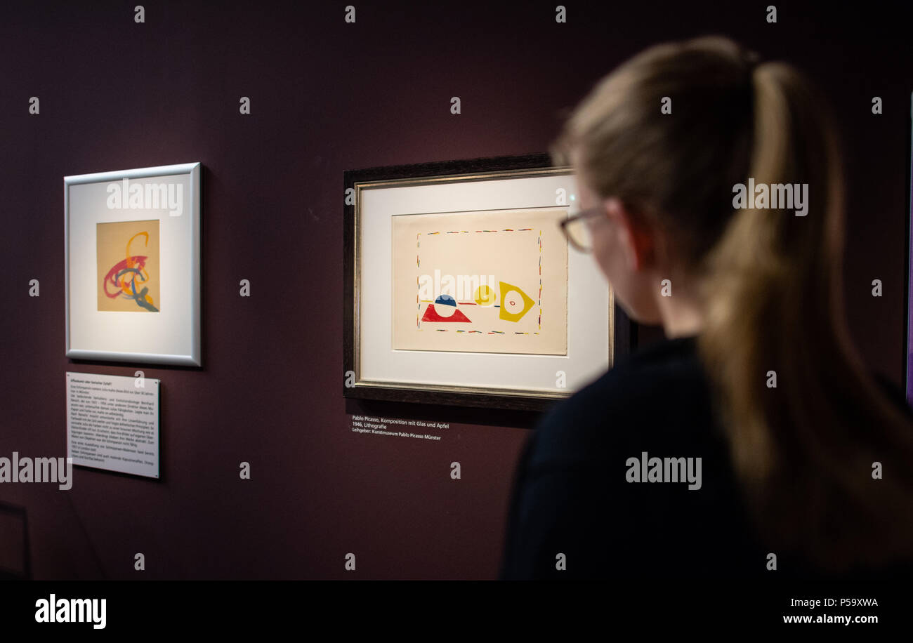 Allemagne, Munster. 26 Juin, 2018. Un visiteur regarde deux photos à l'ouverture de l'exposition du Gehirn - Intelligenz, Bewusstsein, Gefühl' (lit. 'Le cerveau - l'intelligence, la conscience et les sentiments') au Musée des Sciences Naturelles de LWL. Sur la gauche est 'art' ape qui un chimpanzé nommé Julia peint à Muenster il y a plus de 50 ans. Sur la droite est une lithographie de l'année 1946 par Pablo Picasso portant le titre "Composition avec du verre et apple'. Credit : Guido Kirchner/dpa/Alamy Live News Banque D'Images