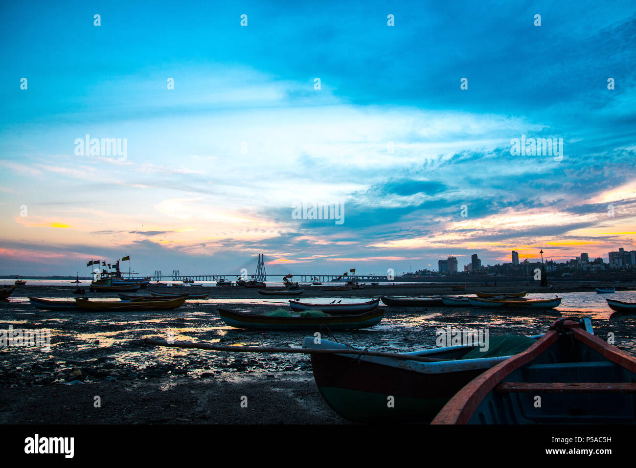 Silhouette de bateaux de pêche à marée basse, le coucher du soleil près de Mahim bay - Mumbai, Maharashtra, Inde. Et Worli Link, Bandra Pali Hill dans l'arrière-plan. Banque D'Images