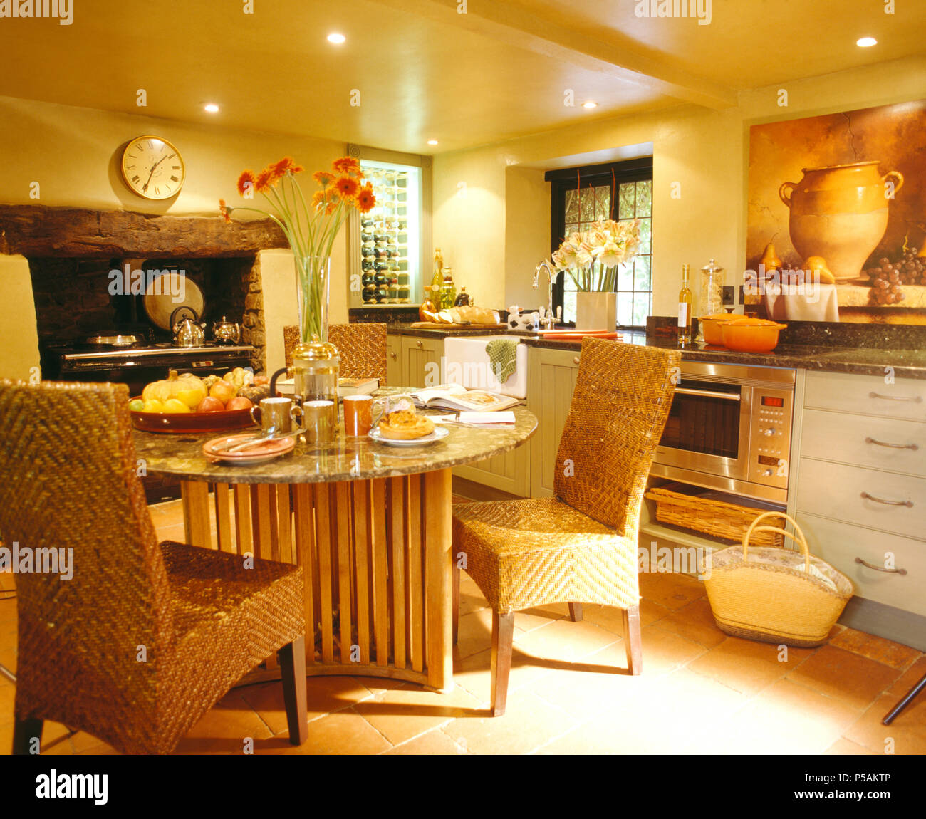 Retour à grandes chaises en osier tissé à granite +table à manger en bois dans une cuisine moderne avec un éclairage vers le bas Banque D'Images