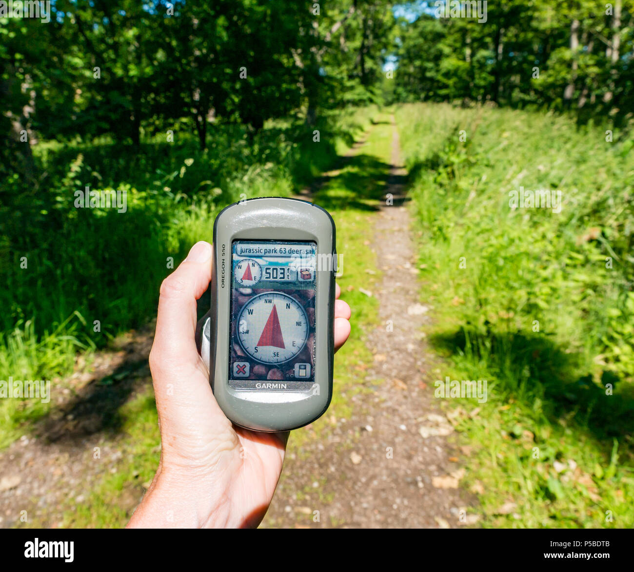 Gros plan de la main d'une femme tenant un GPS Garmin pointant vers un Trésor à 500 mètres sur un sentier de campagne, Écosse, Royaume-Uni Banque D'Images