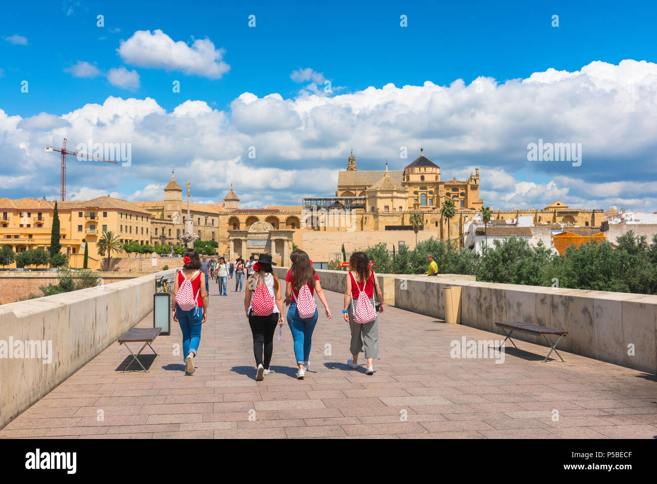 Jeunes femmes amis, vue arrière d'un groupe de jeunes femmes espagnoles traversant le pont romain de Cordoue, avec la cathédrale / la mosquée Mezquita devant vous. Banque D'Images