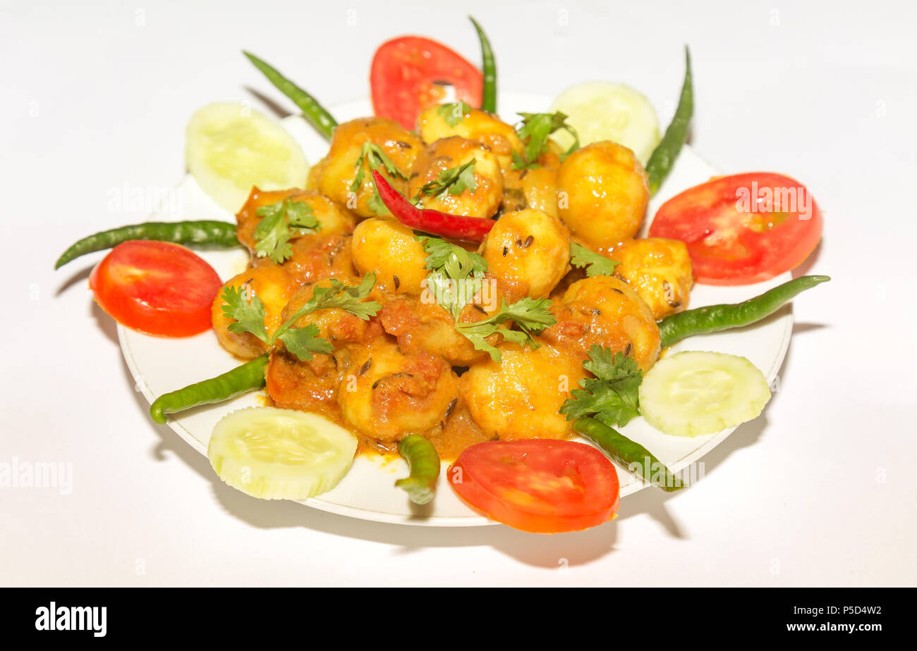 La nourriture végétarienne indienne épicée préparée avec des petites pommes de terre connue sous le nom de Dum Aloo garnie avec le concombre, la tomate et le piment vert. Banque D'Images