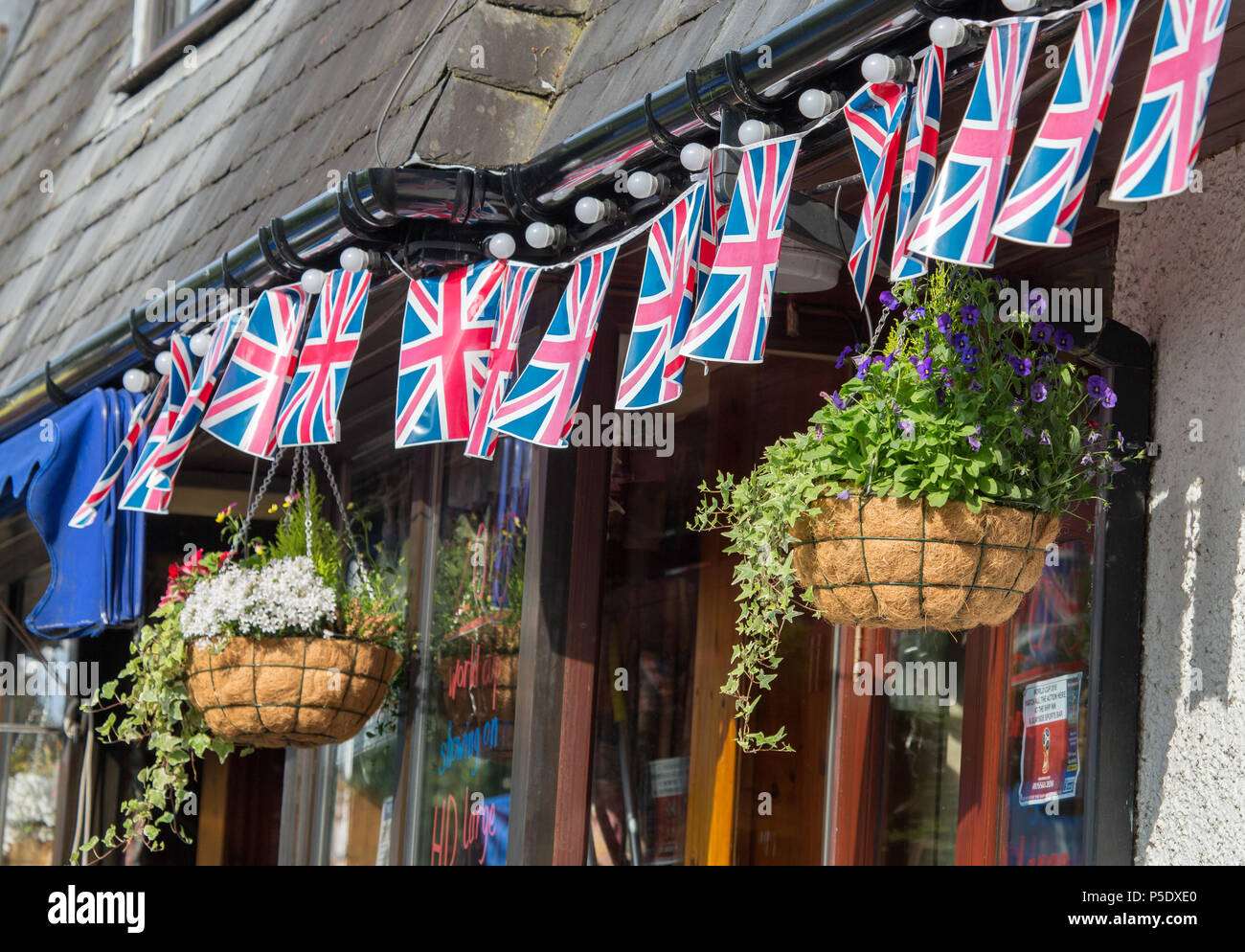 Une rangée de drapeaux Union Jack et deux paniers suspendus à l'extérieur d'une maison publique à Bowness-On-Windermere Banque D'Images