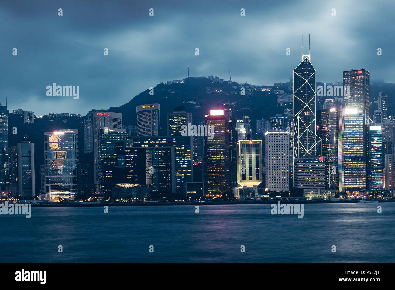 Hong Kong city skyline on Victoria Harbour avec moody ciel gris et les nuages Banque D'Images