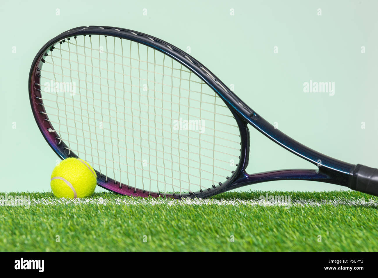 Une raquette de tennis et la balle sur l'herbe avec du fond vert. Banque D'Images
