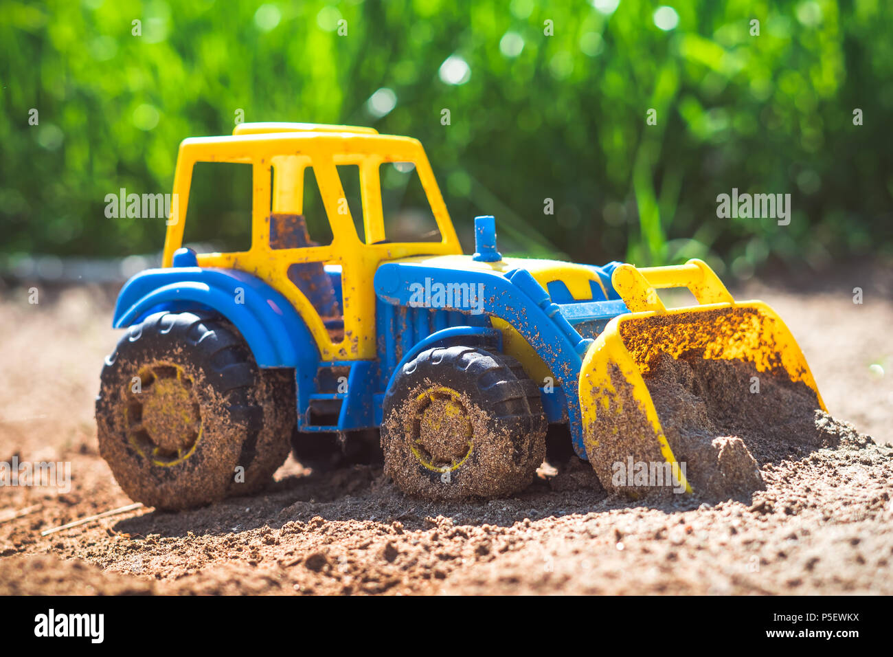Petits enfants bleu jouet tracteur en plastique dans le sable Photo Stock -  Alamy