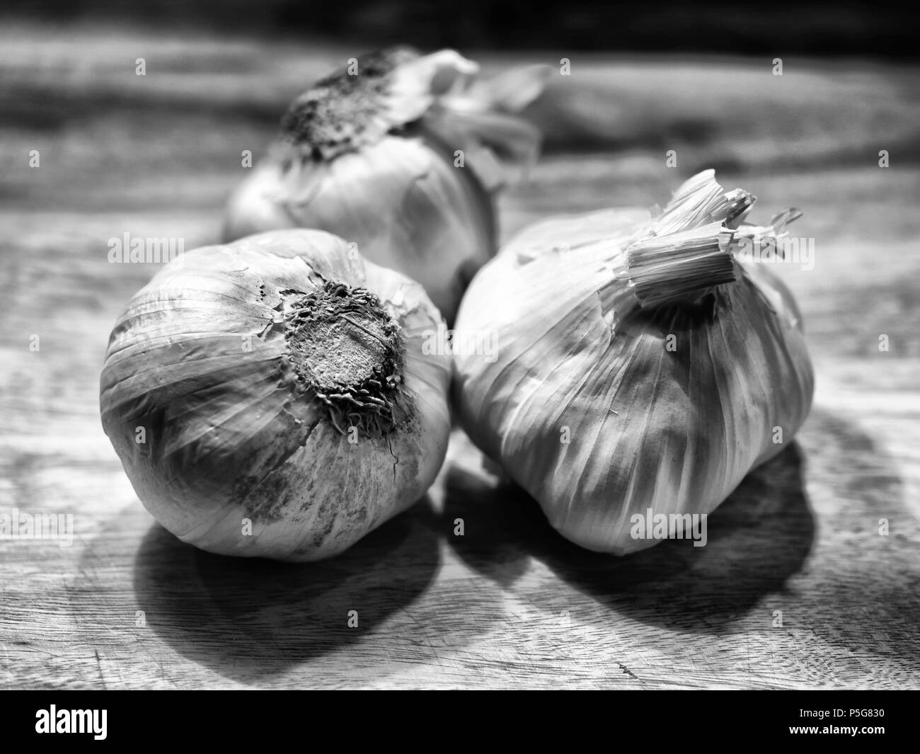 Ail noir et blanc affiché sur une planche à découper. Banque D'Images