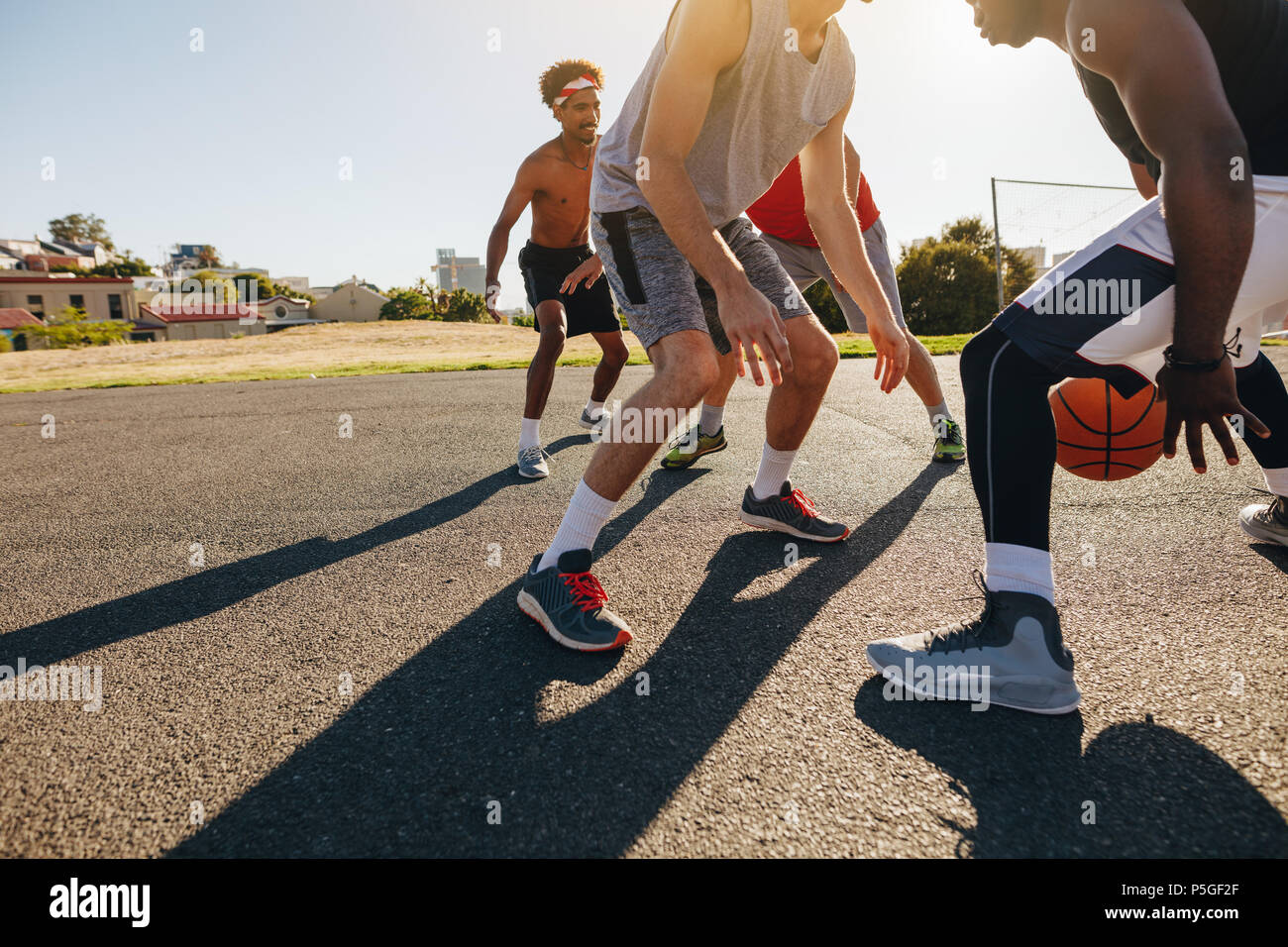 Les hommes jouant au basket-ball jeu sur une journée ensoleillée. Les hommes exerçant des compétences de basket-ball dans l'aire de jeu. Banque D'Images