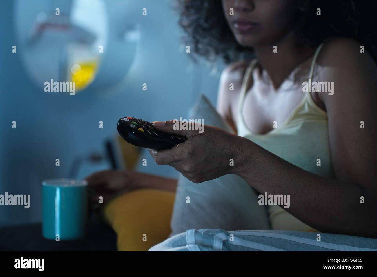 Black Woman Changing TV Channel avec télécommande dans la nuit Banque D'Images