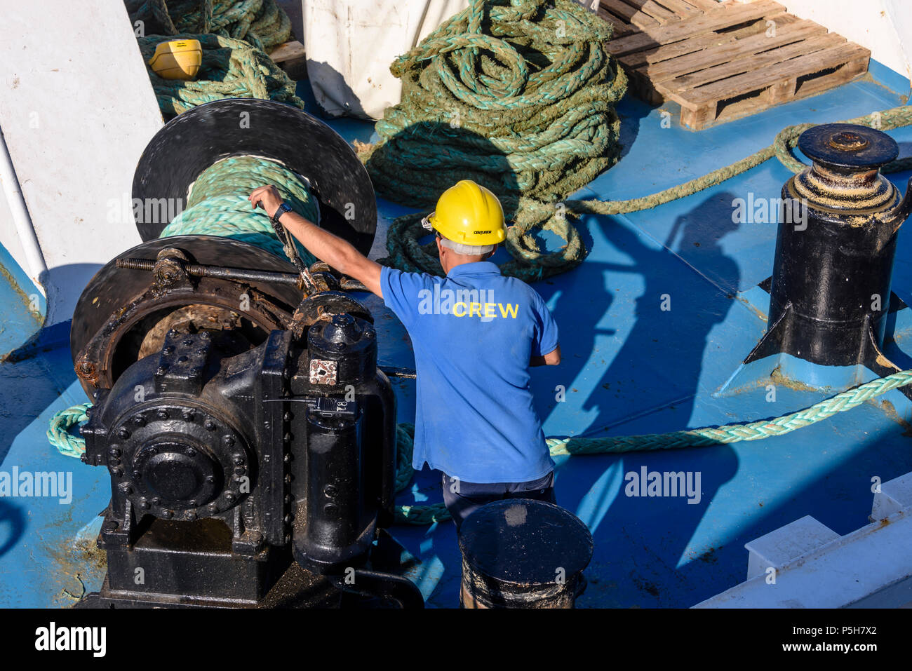 Membre de l'équipage à bord du ferry de Gozo à Malte utilise un treuil pour cordes de tension. Banque D'Images