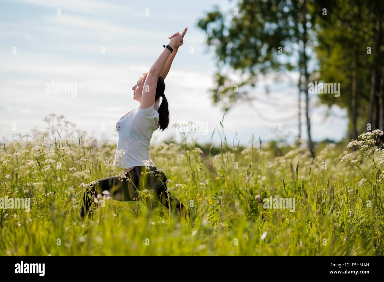 Young woman practicing yoga piscine dans parc. Banque D'Images
