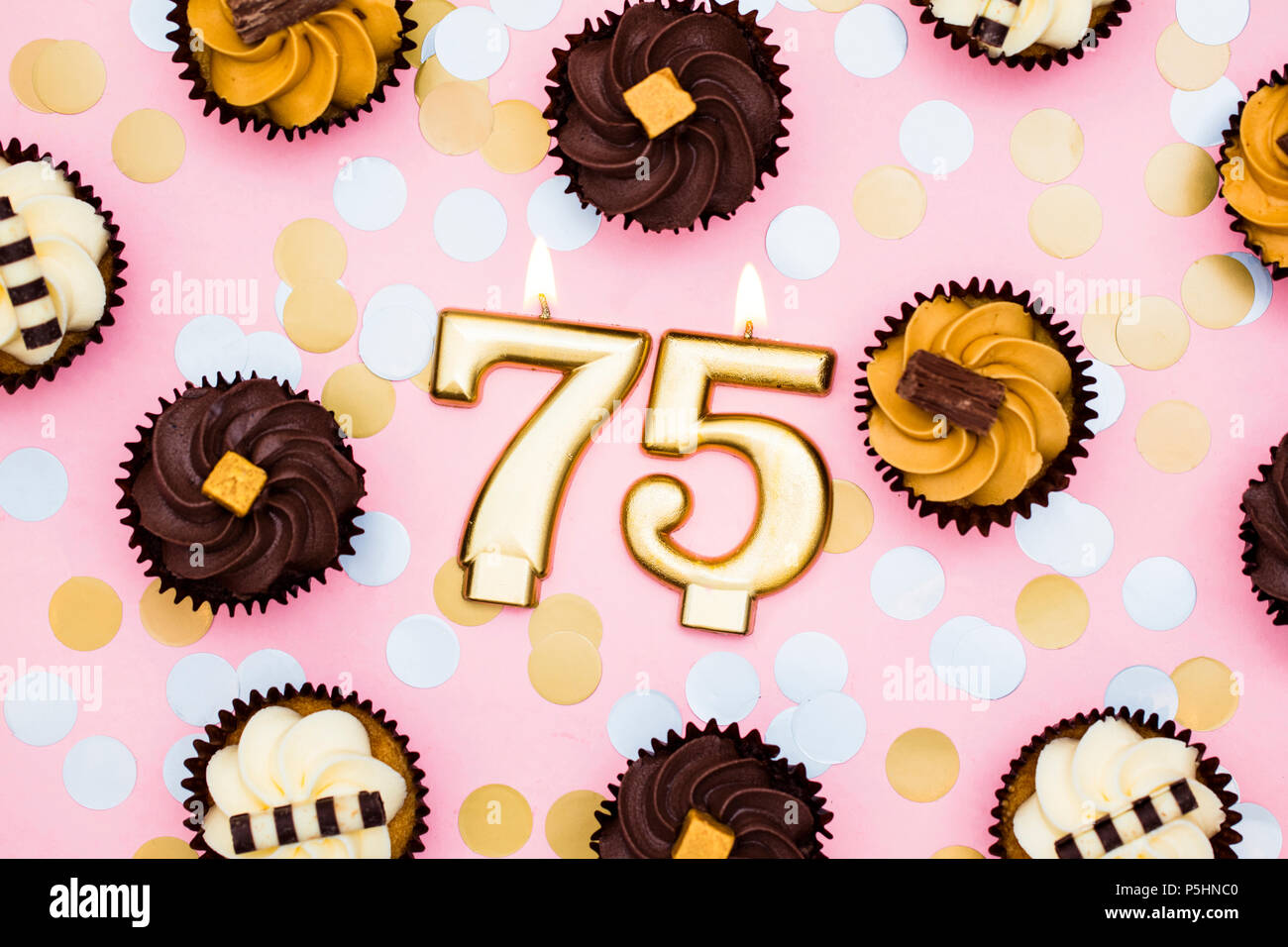 Nombre d'or avec 75 bougies cupcakes contre un fond rose pastel Banque D'Images