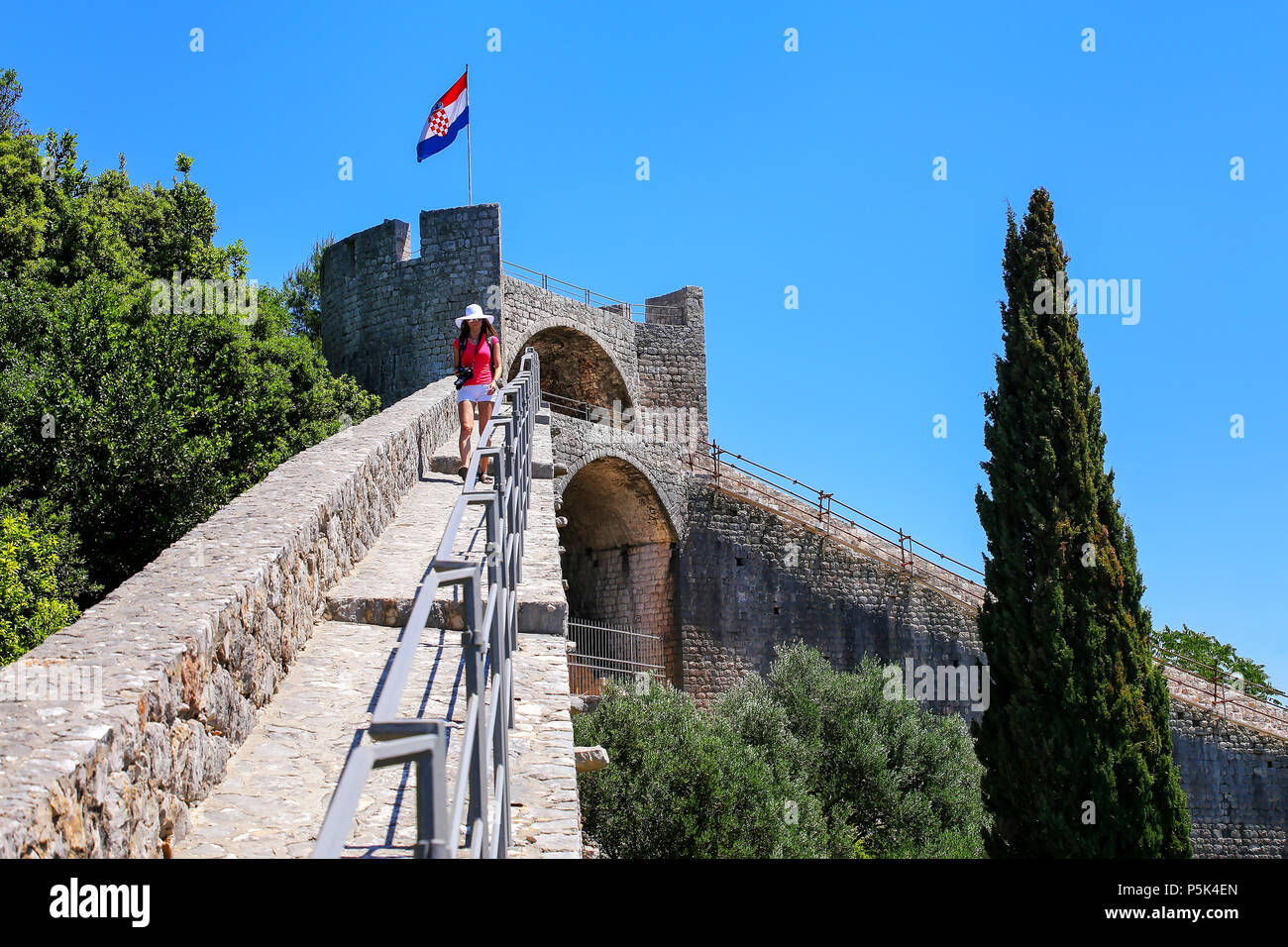 Jeune femme marche sur le mur de défense de la ville de Ston, péninsule de Peljesac, Croatie. Ston est un fort de la République de Raguse Banque D'Images