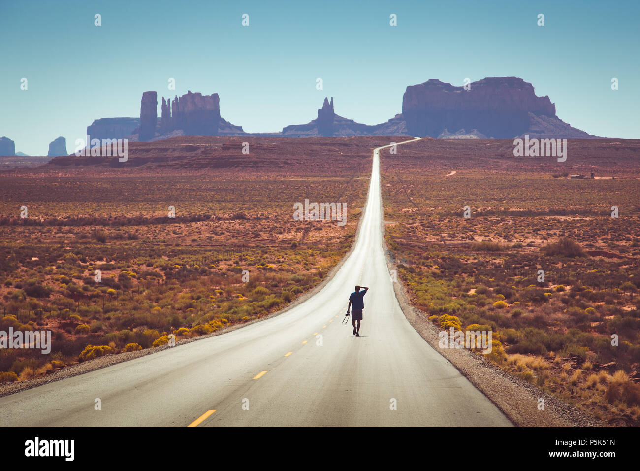Vue panoramique classique d'une jeune personne marcher sur la célèbre route de Forrest Gump à midi à Monument Valley, Arizona, USA Banque D'Images