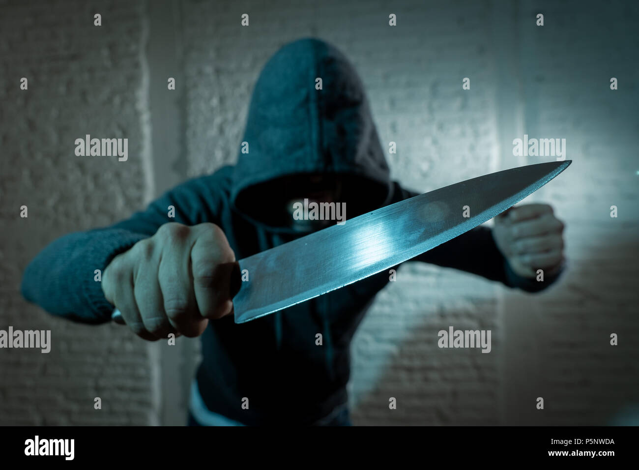 Close up of a mains tenant un couteau de l'homme cagoulé dangereux dans le noir permanent à Londres crime couteau concept. Banque D'Images