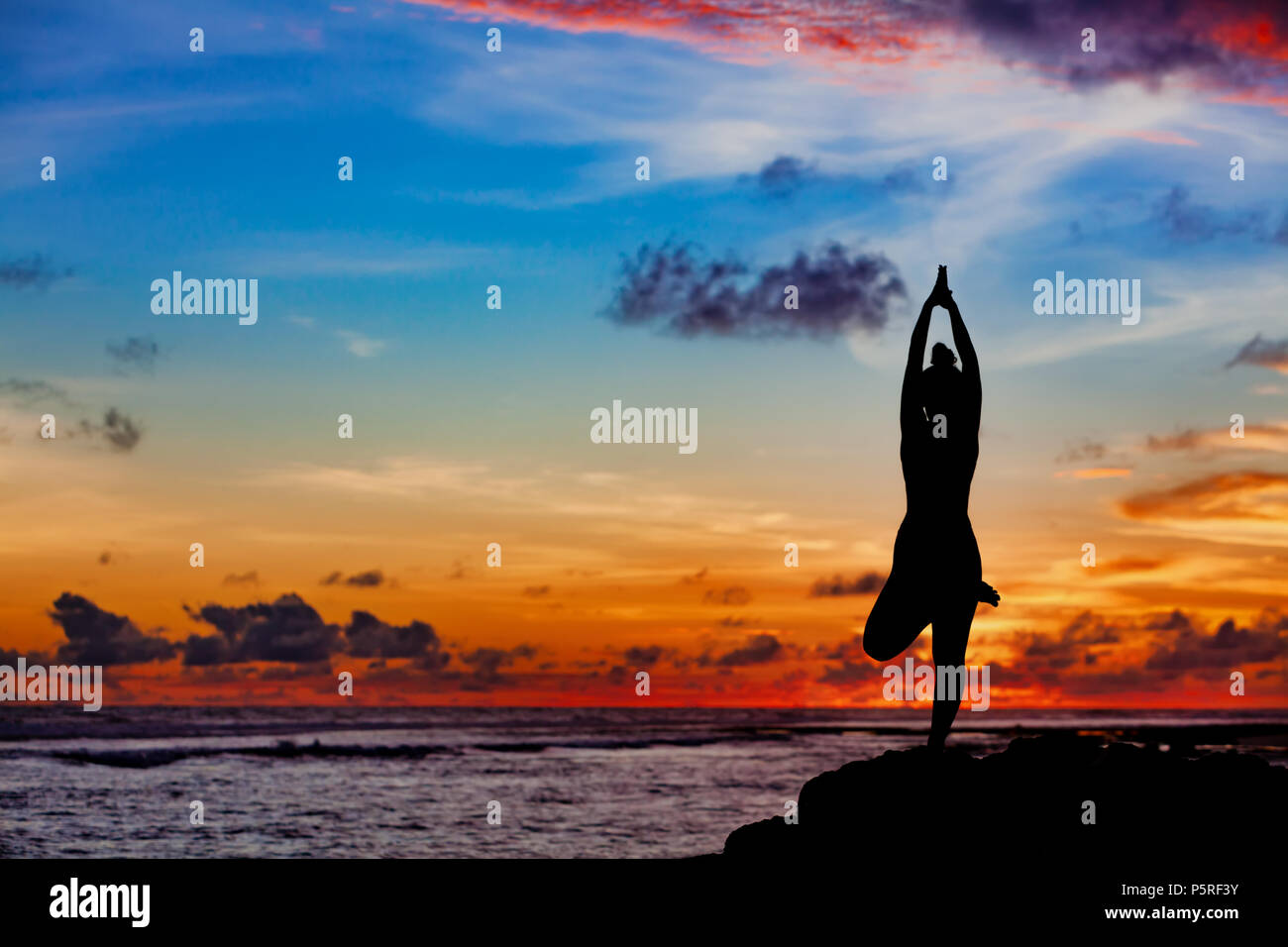 Sunset silhouette méditation Active woman in a stand sur roche de plage pour garder la forme et la santé. Mode de vie sain, de formation de remise en forme, l'activité sportive Banque D'Images