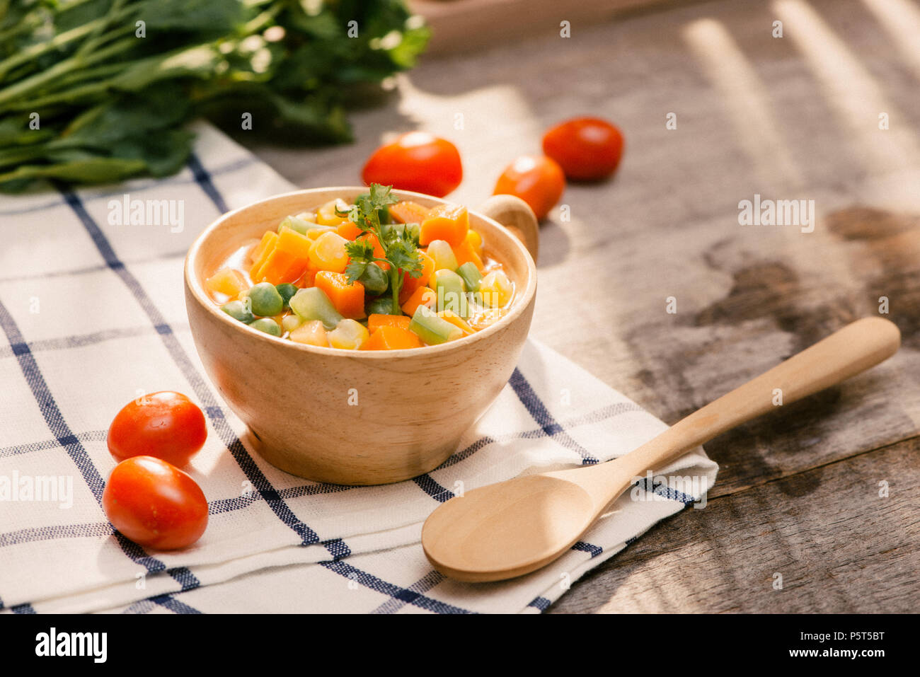 Louche de jeunes légumes fraîchement récoltés à la vapeur y compris les carottes, en Coupe ondulée, de pois et de pommes de terre pour un accompagnement sain pour le dîner Banque D'Images