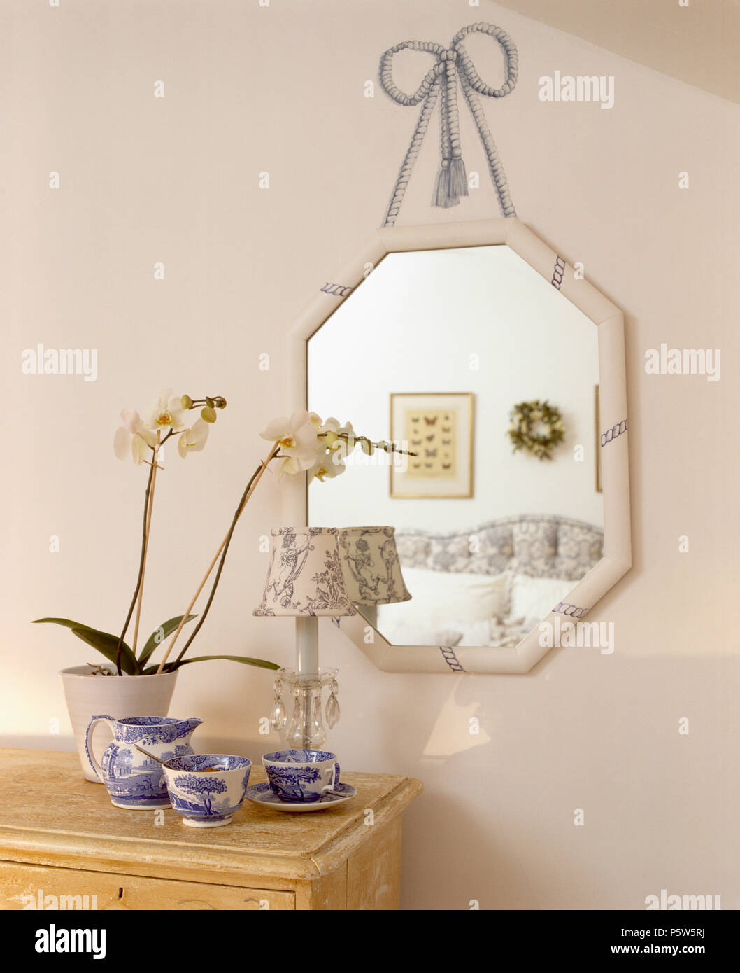 Mirror en trompe-l'oeil effet ruban mural au-dessus de la poitrine avec des orchidées en pot et bleu +blanc Spode verseuse et tasses Banque D'Images