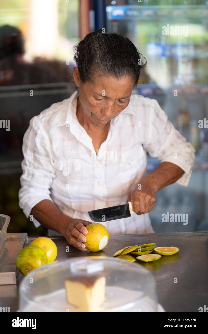 Une femme âgée qui fait du jus d'orange avec un concasseur en Colombie rurale Banque D'Images