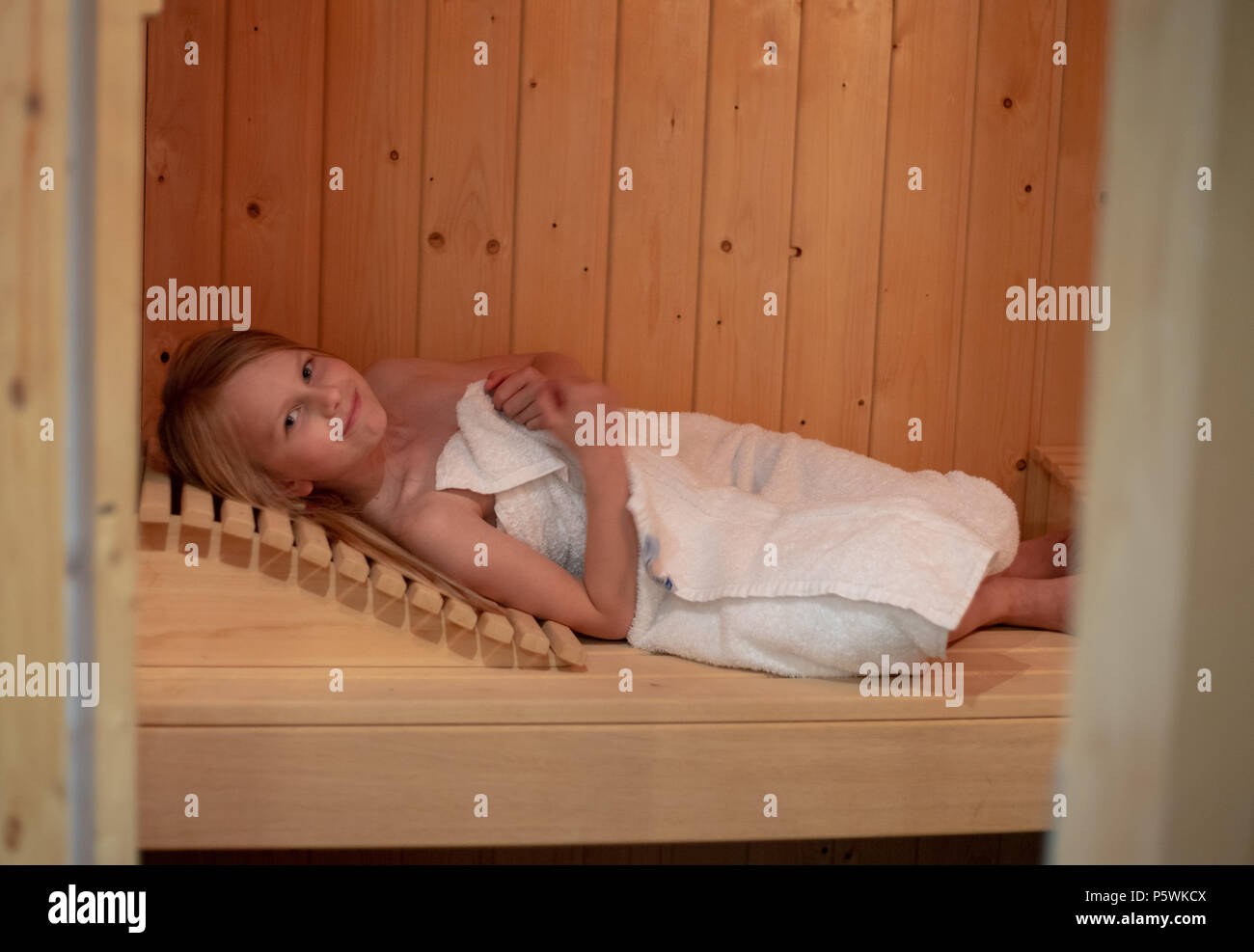 Une fillette de 7 ans se trouve dans une serviette dans un sauna finlandais Banque D'Images