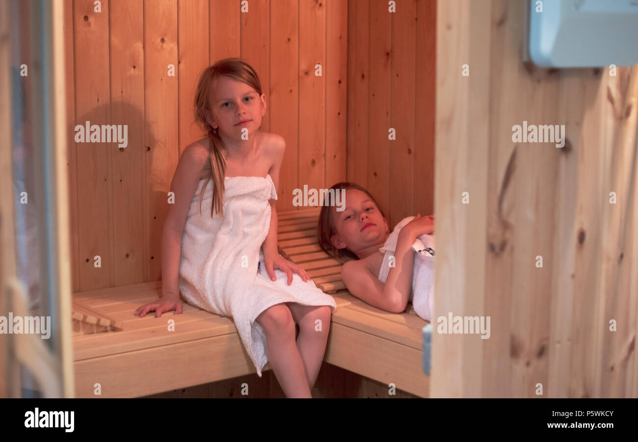 Deux filles ont elles-mêmes enveloppées dans des serviettes et disposent d'un sauna dans un sauna finlandais Banque D'Images