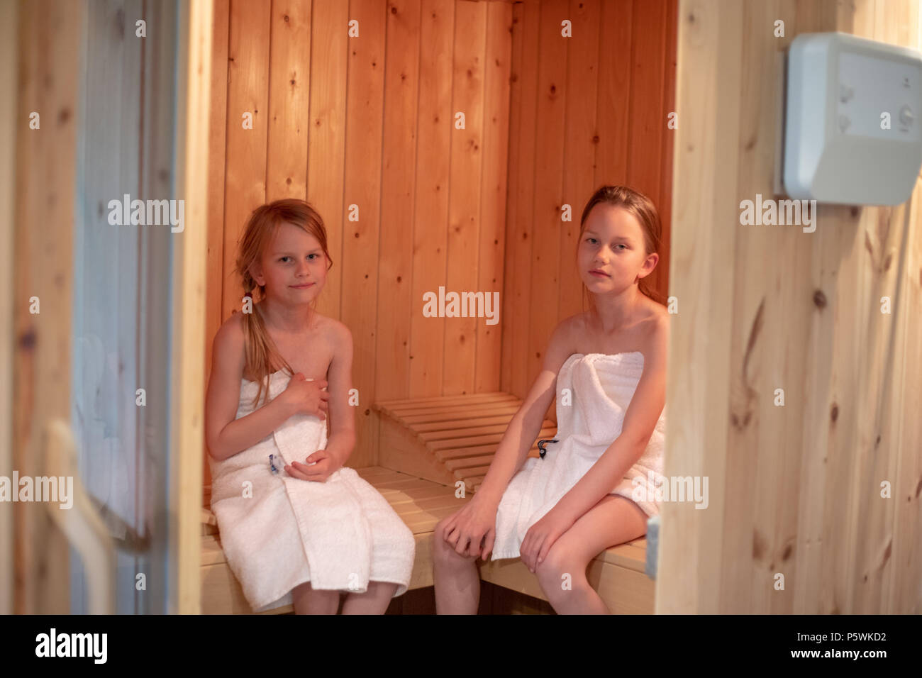 Deux filles ont elles-mêmes enveloppées dans des serviettes et sont assis dans un sauna finlandais Banque D'Images