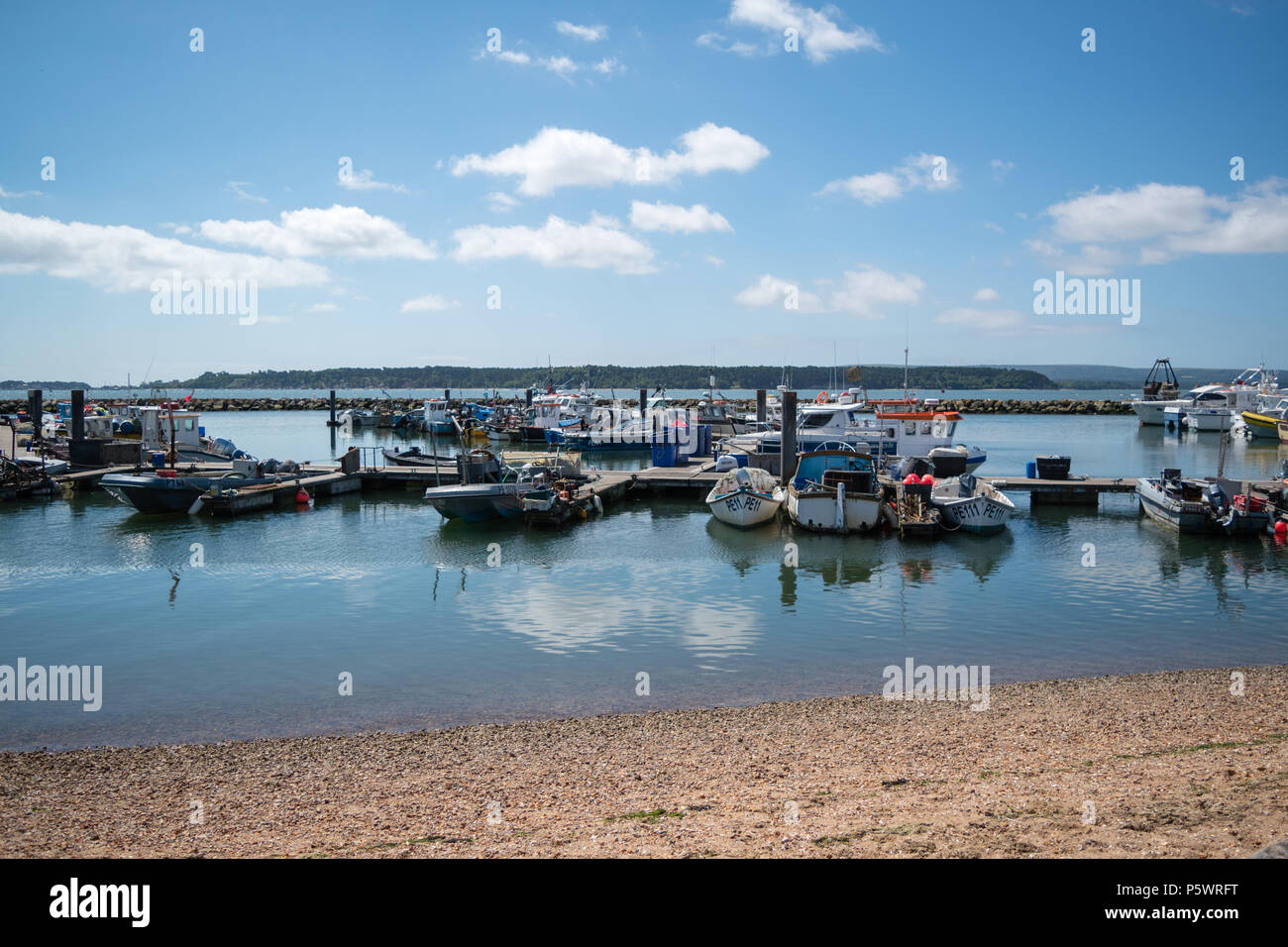 Surplombant les eaux calmes et les bateaux de pêcheurs à quai dans le port de Poole sur une journée ensoleillée avec l'île de Brownsea au loin. Banque D'Images