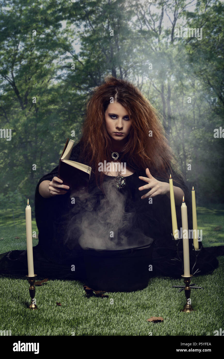 Sorcière avec cualdron et livre de sorts dans la forêt Banque D'Images