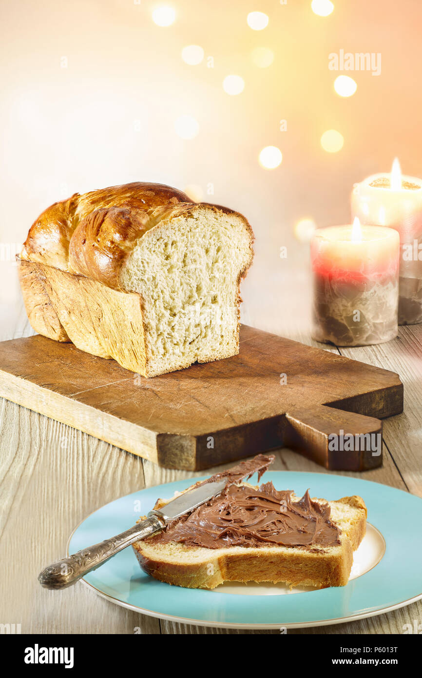 Tranche de pain brioché enduite de crème au chocolat, en vacances d'hiver avec de l'humeur et la lumière des bougies. Banque D'Images