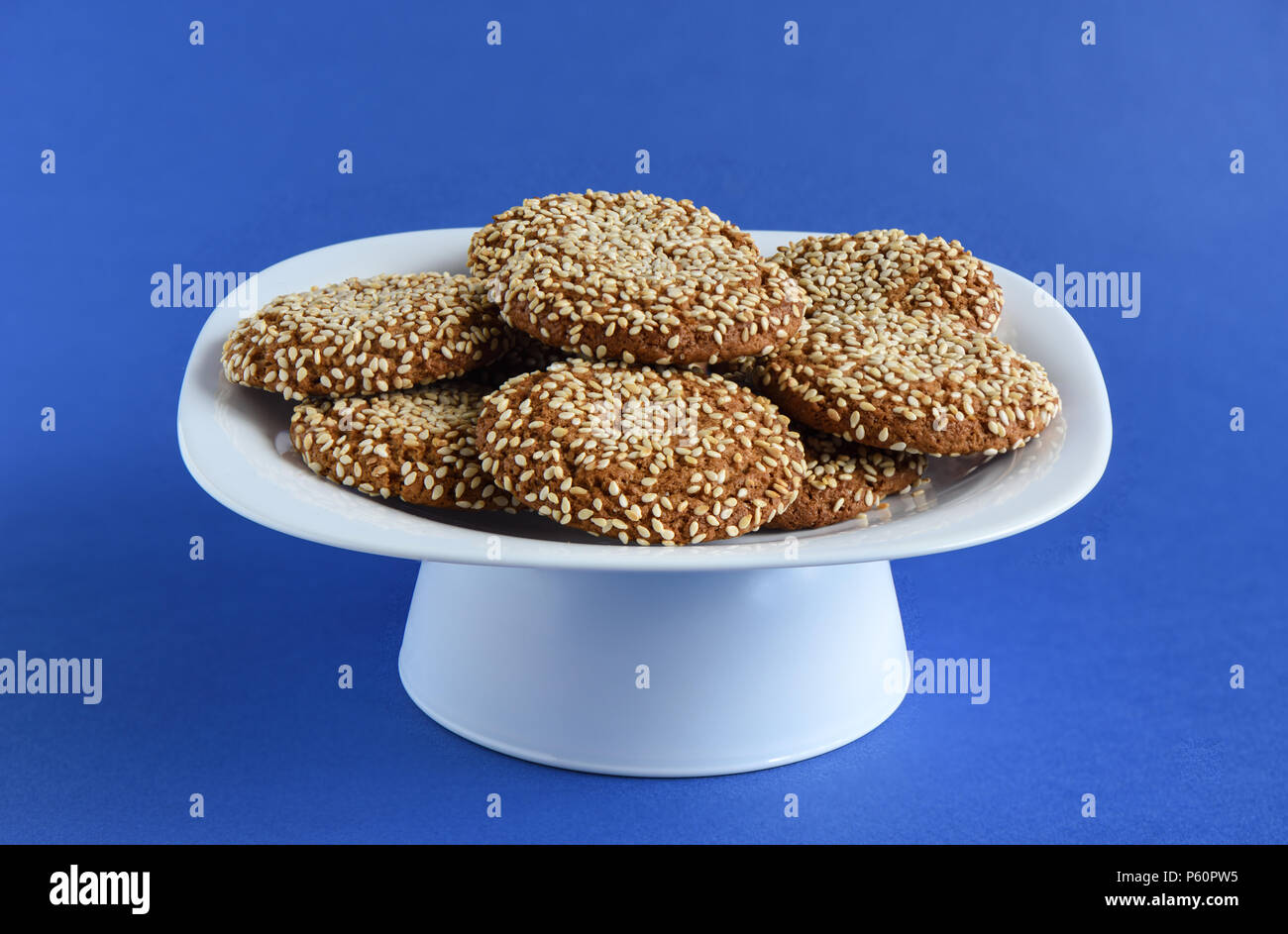 Biscuits aux graines de sésame dans une assiette blanche sur un fond violet Banque D'Images