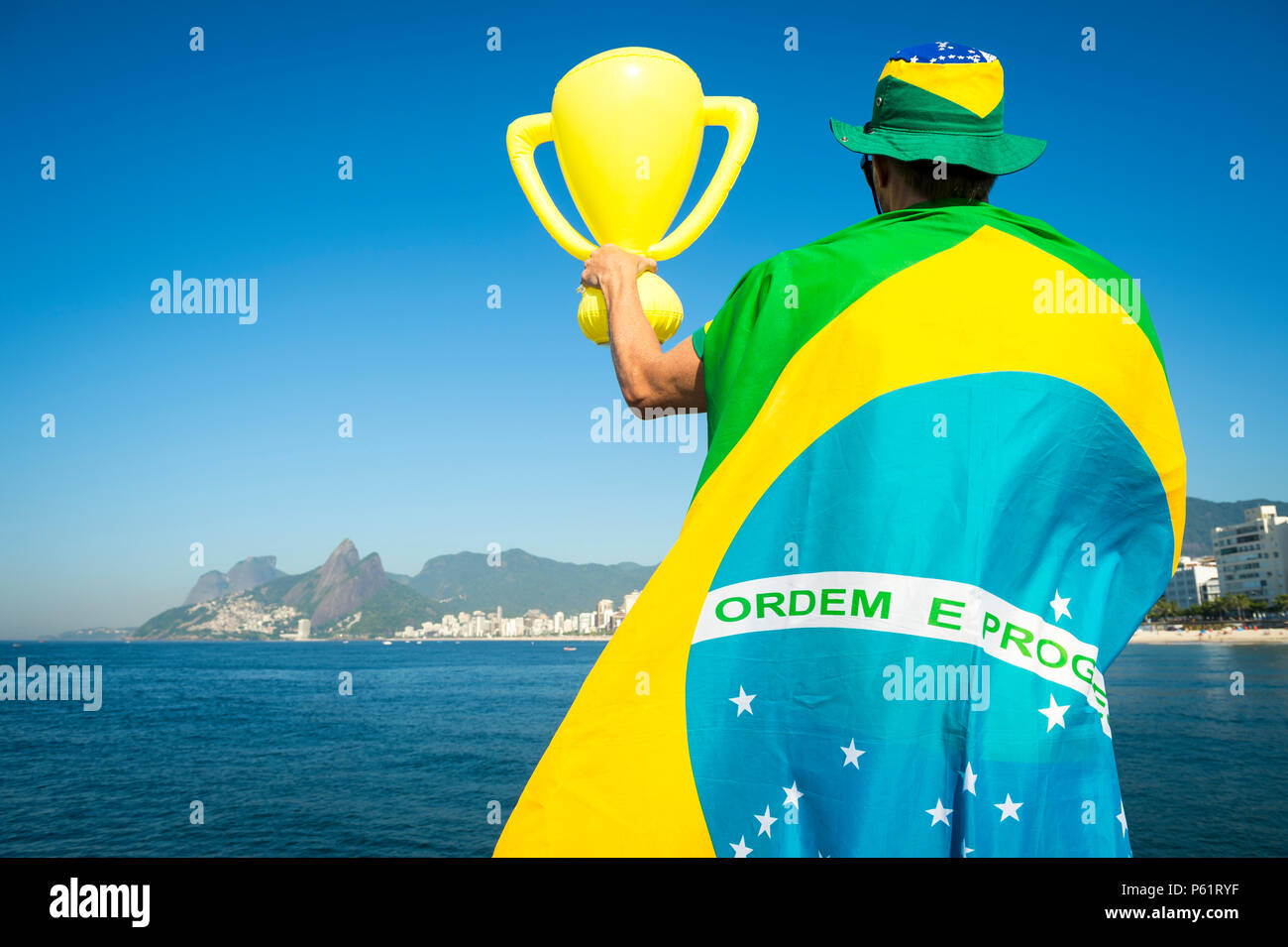 Fan de football brésilien enveloppée de drapeau géant et hat en face de la plage d'Ipanema Ville Rio de Janeiro. Banque D'Images