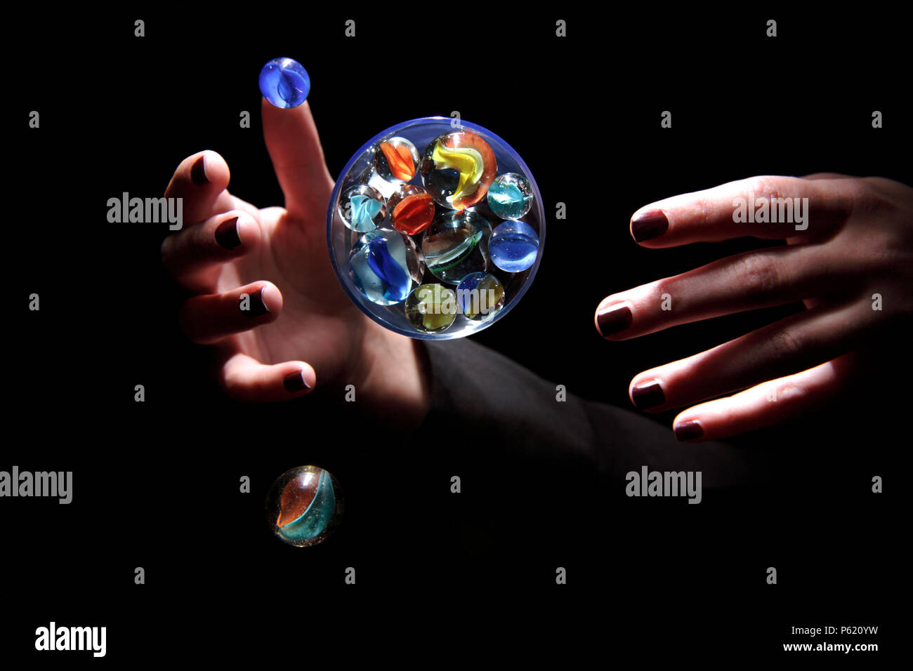 Une paire de mains contrôler une bille en verre sphère qui ressemble à la terre avec de petites lunes. Banque D'Images