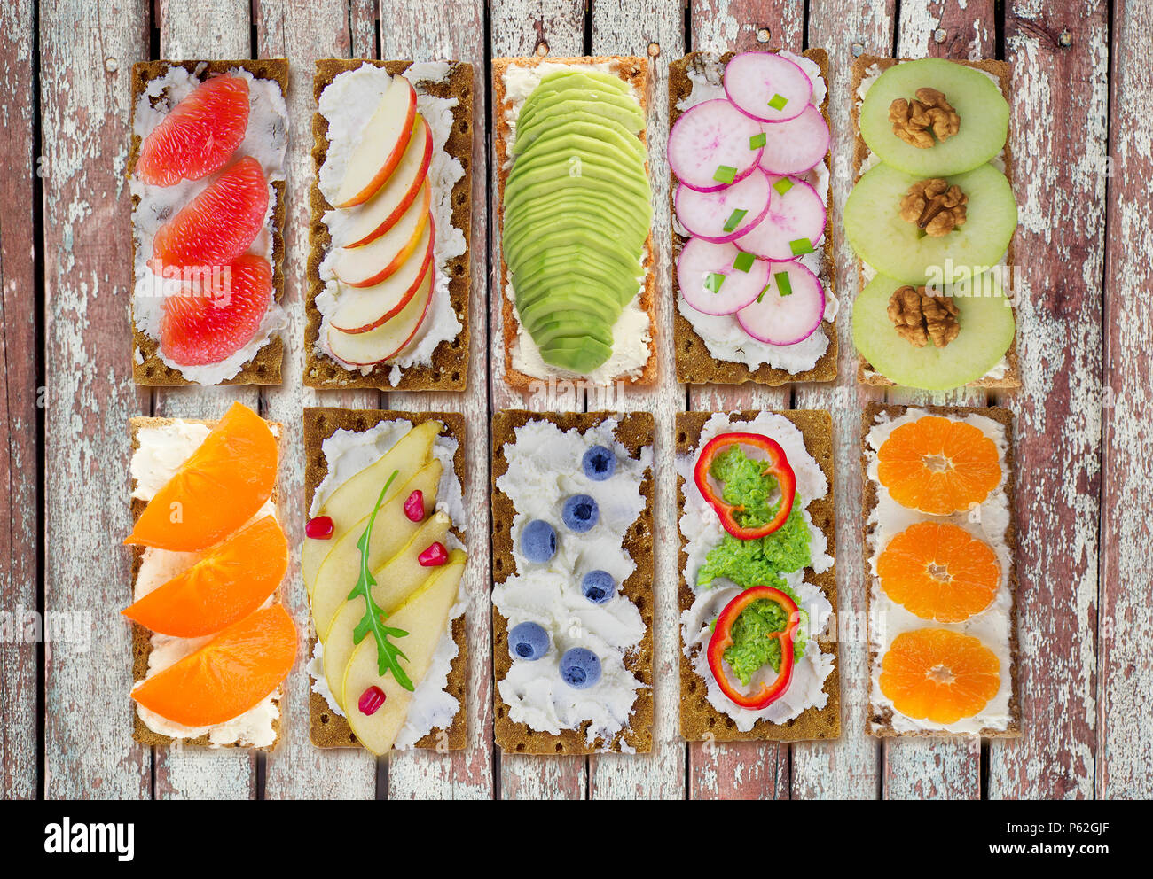 Sandwiches au fromage à la crème et les baies fraîches, fruits et légumes. Snack apéritif frais sain avec des biscottes. Banque D'Images