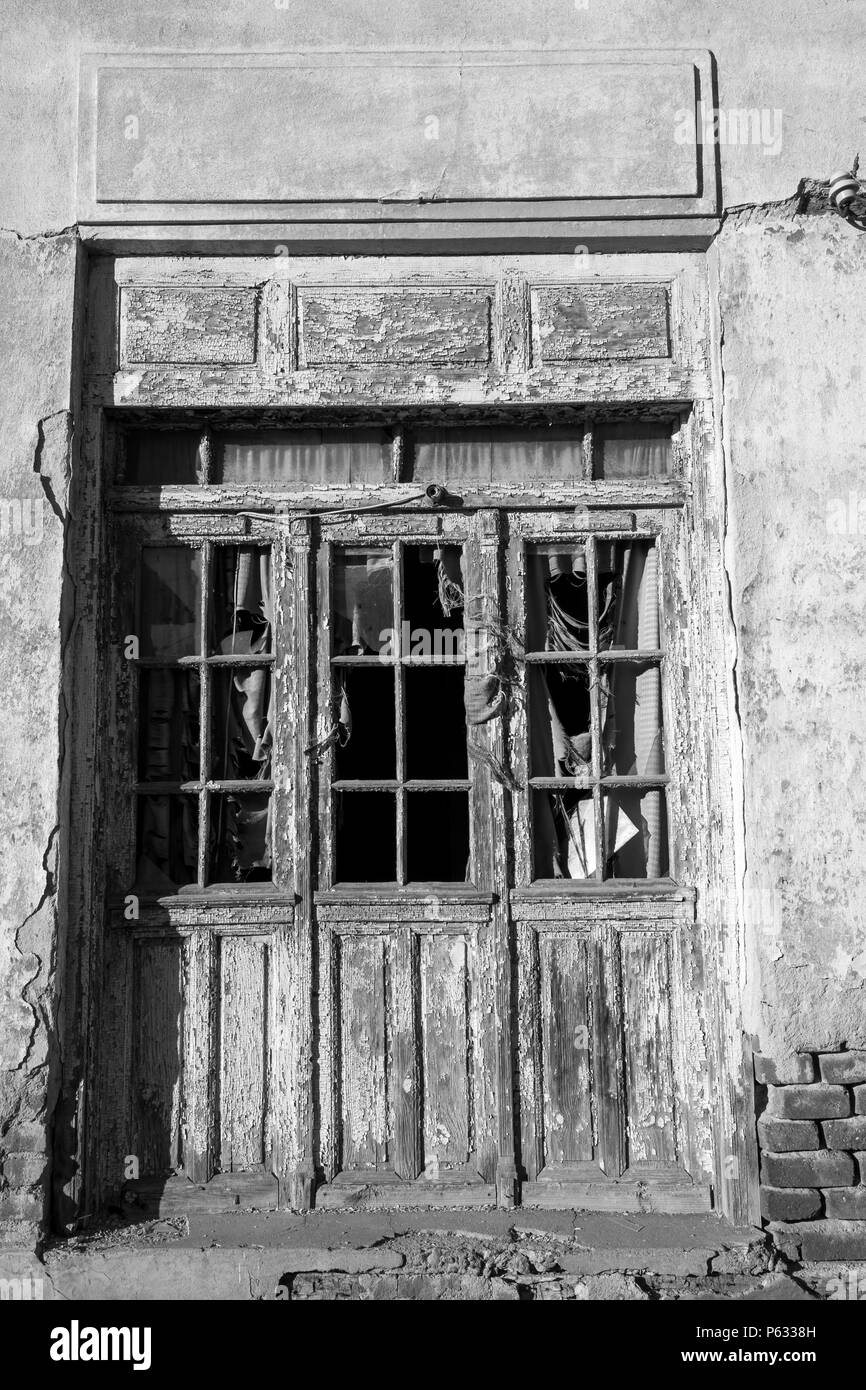Porte en bois patiné avec peinture écaillée d'une maison abandonnée dans le village de Chavdar, Bulgarie. Image en noir et blanc Banque D'Images