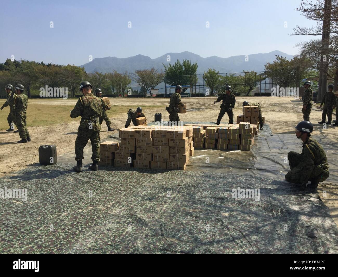 Forces d'autodéfense japonaises membres de services d'aide aux victimes du séisme de la pile des articles qui ont été déchargées d'un MV-22B Balbuzard appartenant au milieu marin de l'Escadron 265 rotor basculant (renforcée), 31e Marine Expeditionary Unit, 19 avril 2016 à Hakusui Sport Park, Kumamoto, Japon. 31e MEU marines sont des JSDF secours par suite des tremblements de terre qui a frappé l'île de Kyushu au début de la semaine, à la demande du Gouvernement du Japon. La 31e MEU est le seul de l'avant sans cesse déployés-MEU et demeure la force du Marine Corps en préparation dans la région Asie-Pacifique. (U.S. C Marine Banque D'Images