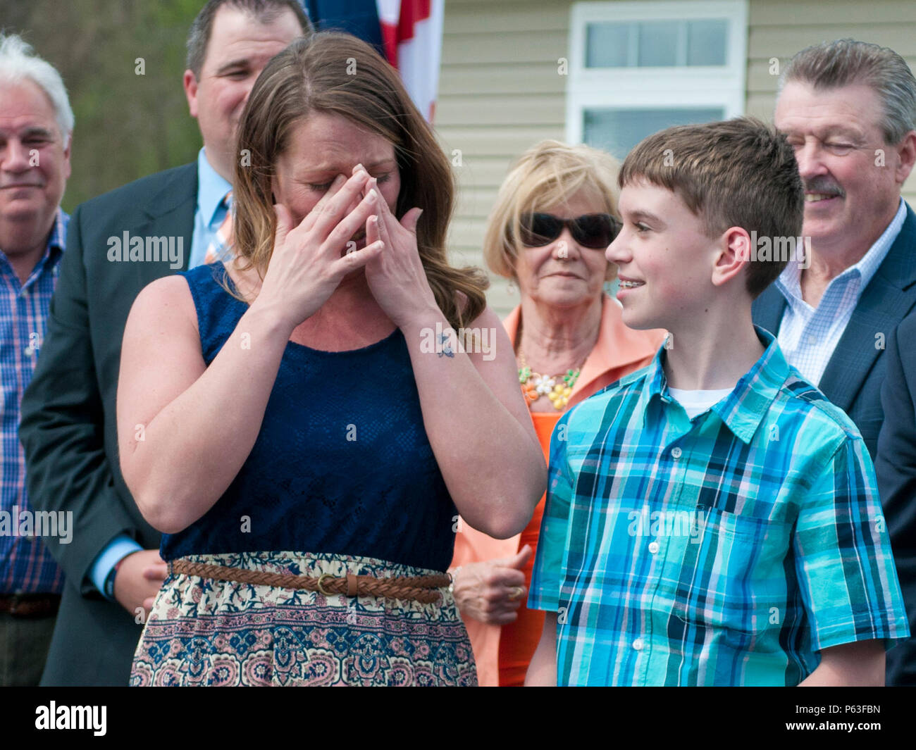 Le s.. Michelle Satterfield, avec le 14e Détachement de quartier-maître, essuie les larmes que sa nouvelle maison est révélé derrière durant sa cérémonie à McKeesport, Pennsylvanie, le 25 avril 2016. Satterfield reçoit une maison construite par les étudiants de l'McKeesport Area High School et Stephen Siller Tunnel à la base de tous les tours du travail bénévole qu'elle a accompli au cours des dernières années. (U.S. Photo de l'armée par le sergent. Dalton Smith / relâché) Banque D'Images