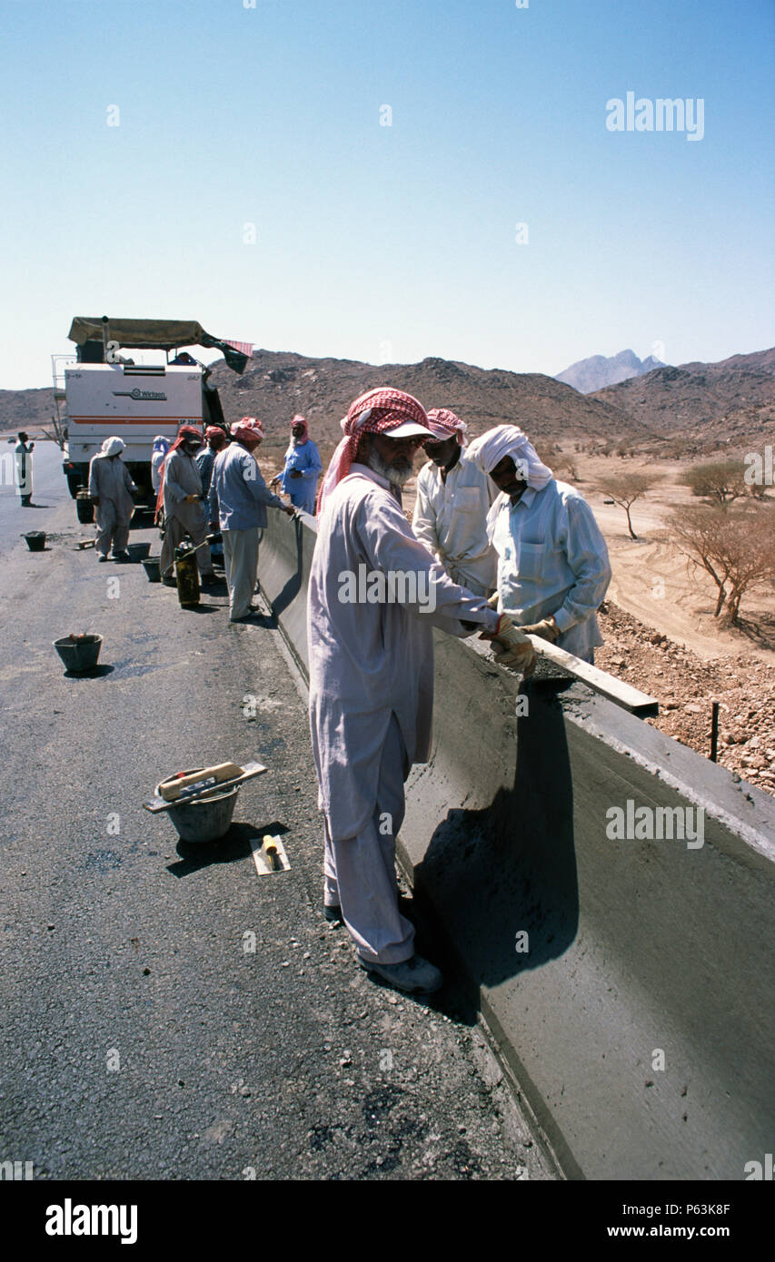 Slipforming barrière routière sur la Médina Yanbu section - travaux de finition à la truelle sur le béton humide encore -- à Jeddah, Arabie saoudite l'autoroute Medina Banque D'Images