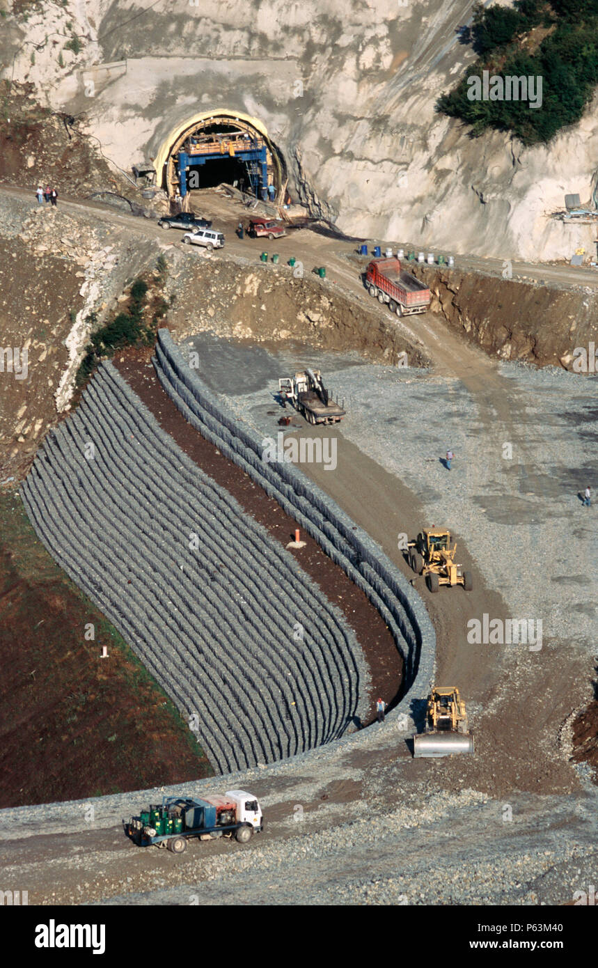 Les racloirs et le niveau de remplissage des bulldozers de pierre concassée pour un remblai renforcé face gabions formant l'approche d'une entrée du tunnel sur l'autoroute Egnatia Banque D'Images