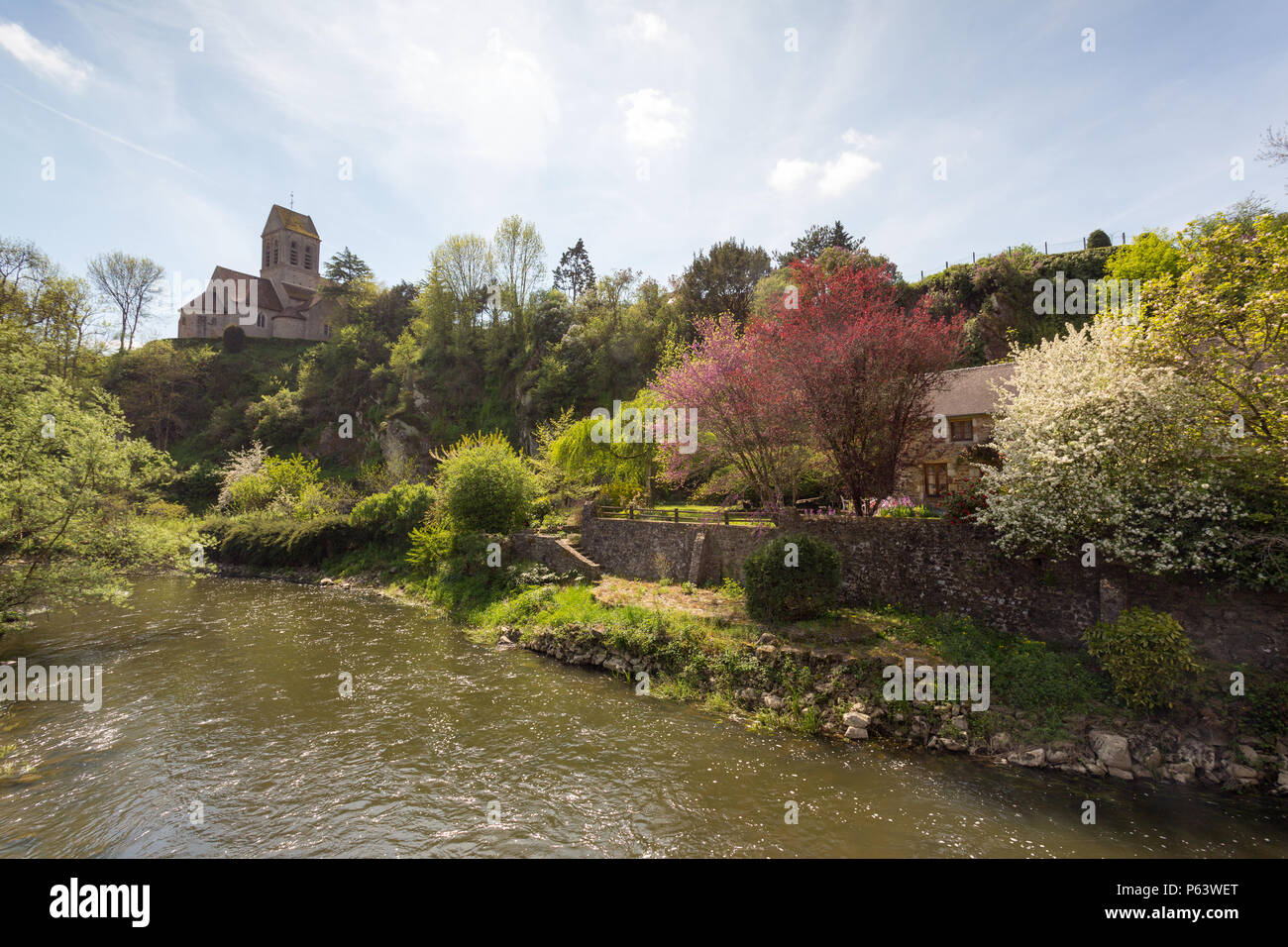 Saint-Ceneri-le-Gerei, Normandie France. La rivière Sarthe dans un cadre boisé avec l'ancienne église en arrière-plan. Banque D'Images