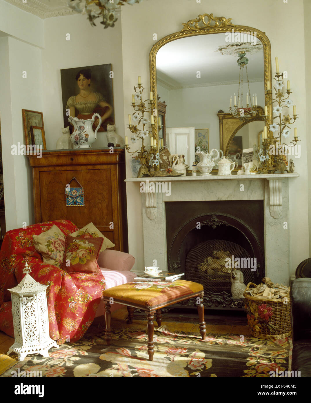Miroir doré antique au-dessus de cheminée avec des candélabres dans la salle de séjour avec un fauteuil rouge jeter sur Banque D'Images