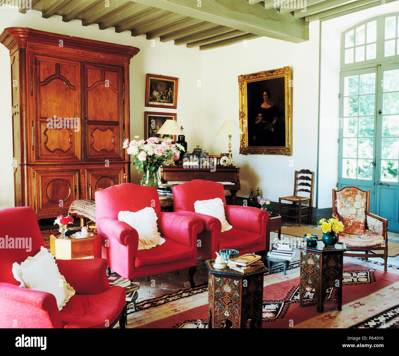 Fauteuils rose profond et armoire antique en français pays salon avec une paire de tables marquetées marocain Banque D'Images