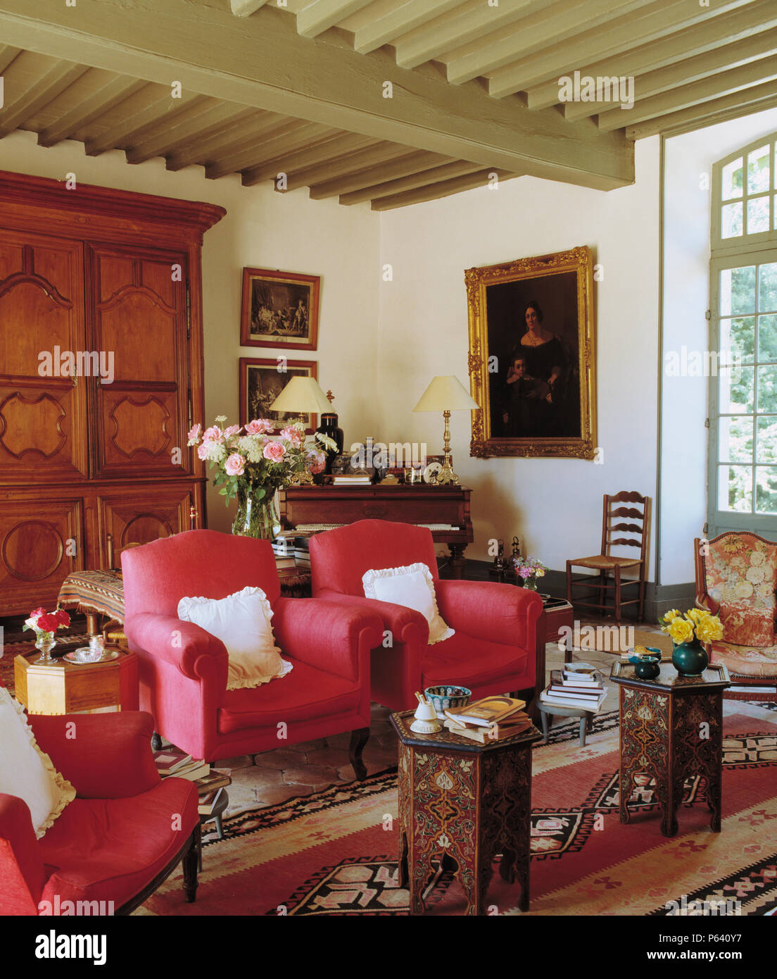 Fauteuils rose profond et une paire de tables marquetées marocain en français pays salon avec poutres peintes Banque D'Images
