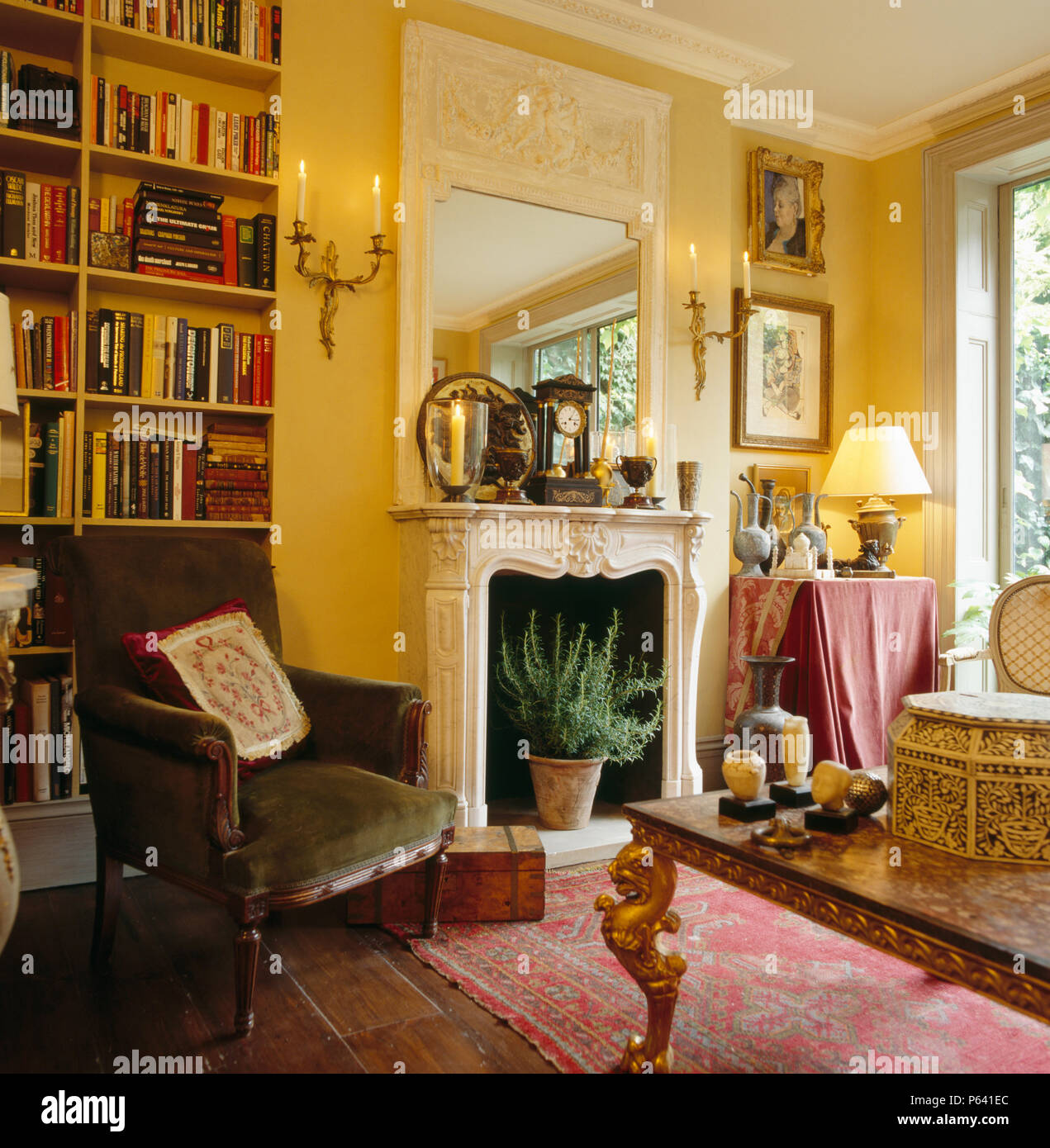 Victorien velours vert chaise à côté de la cheminée de marbre avec miroir trumeau ancien dans le salon jaune Banque D'Images