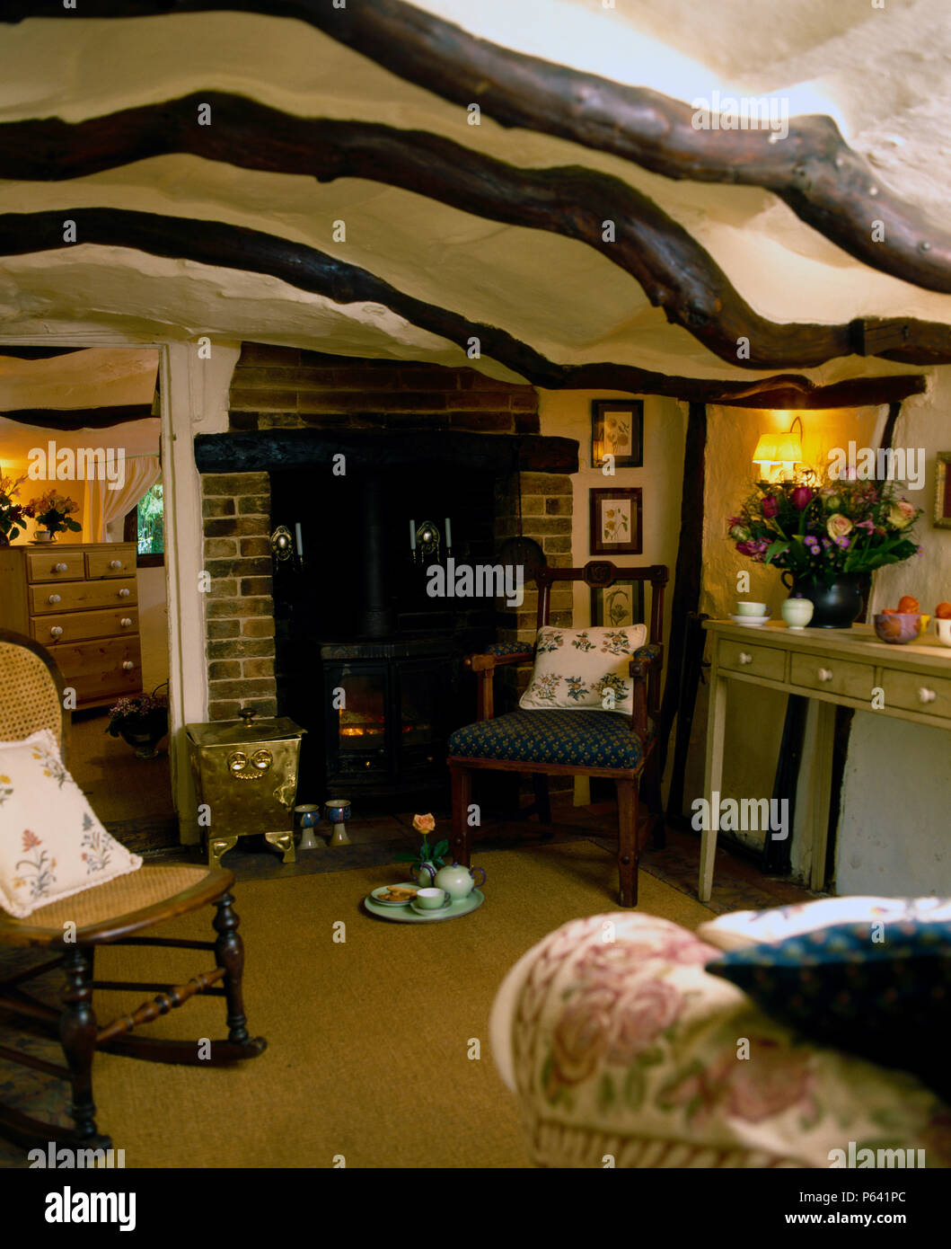 Rocking chair en bois cintré en cottage au plafond bas, salon avec poêle à bois et tapis en sisal Banque D'Images