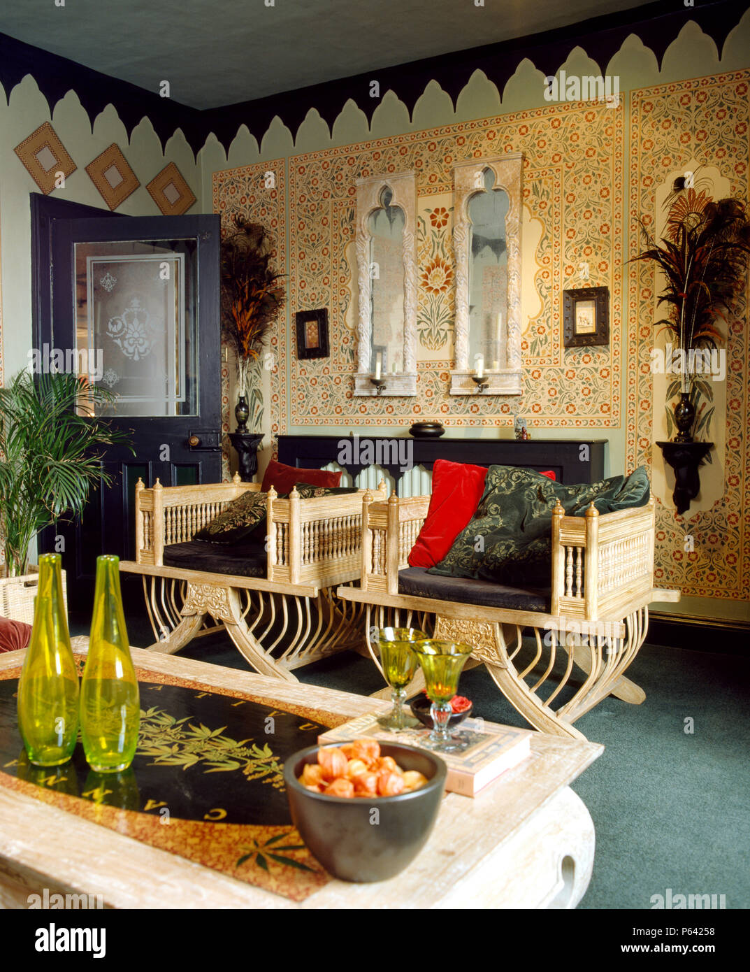 Fauteuils en bois de style indien dans le pays de séjour avec des murs au pochoir de façon décorative Banque D'Images