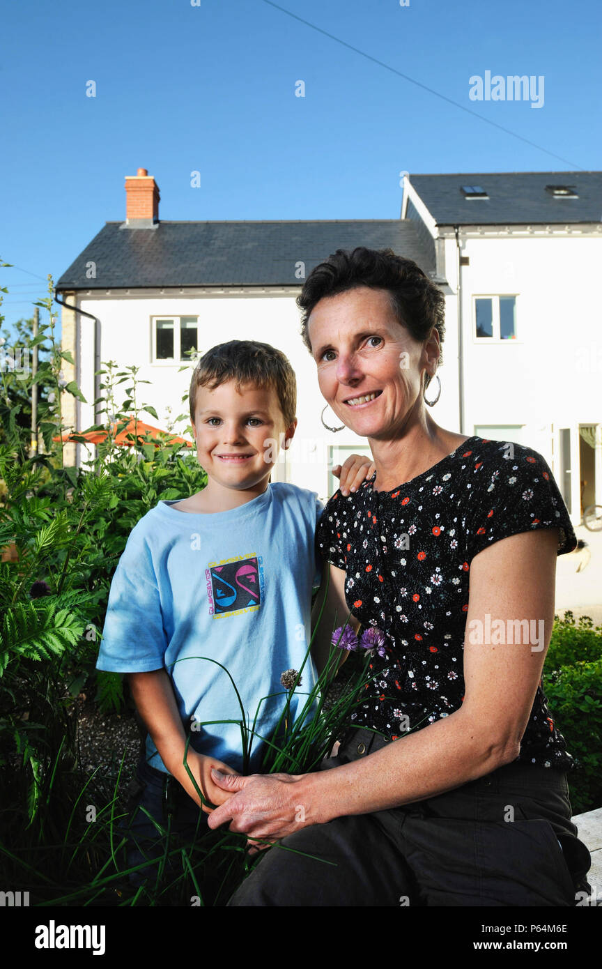 La mère et le fils à l'extérieur de maison écologique à Chewton Mendip, Somerset, UK avec une pompe à chaleur et système de ventilation à récupération de chaleur Banque D'Images
